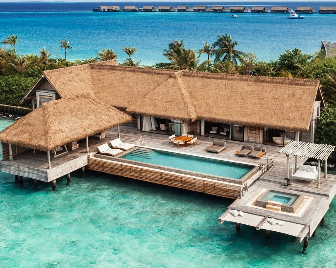 Luxury overwater bungalow with private pool and thatched roof in turquoise Maldivian waters.